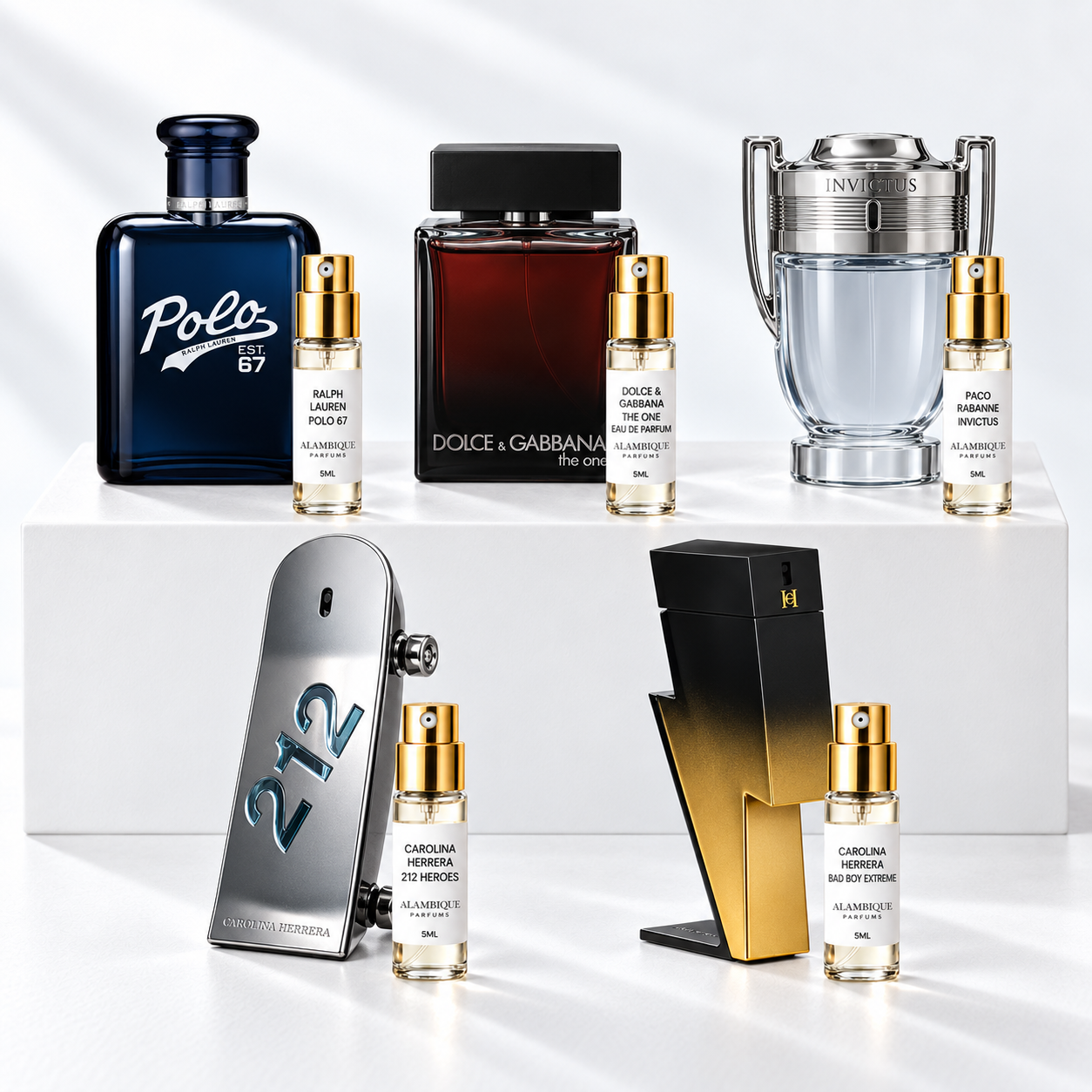 Discovery set Alambique: RALPH LAUREN POLO 67, DOLCE & GABBANA THE ONE EAU DE PARFUM, PACO RABANNE INVICTUS, CAROLINA HERRERA 212 HEROES, CAROLINA HERRERA BAD BOY EXTREME. Decants con etiquetas blancas y atomizadores dorados junto a las botellas de referencia.