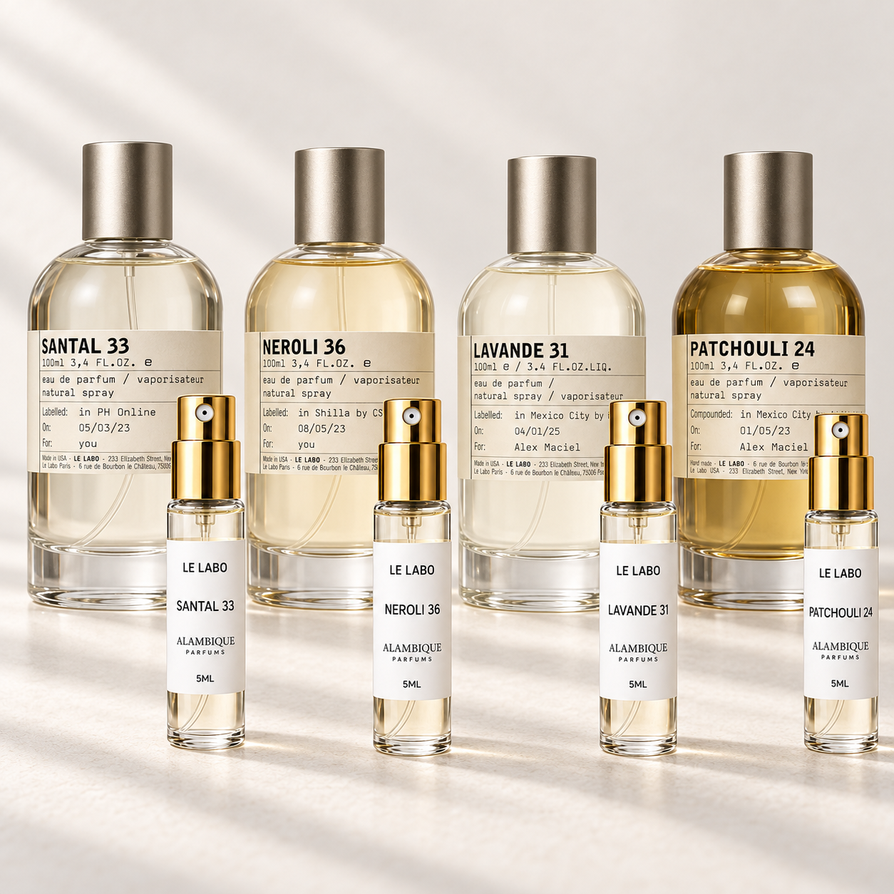 Le Labo Discovery Set: cuatro decants con etiquetas blancas; botellas originales al fondo solo como referencia.